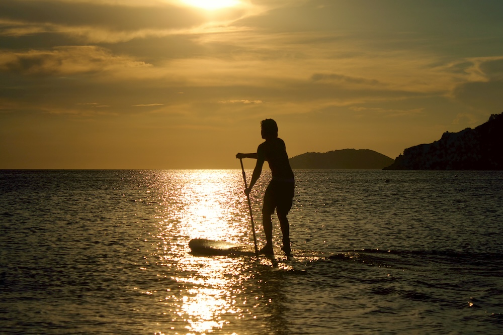 man paddleboarding at sunset