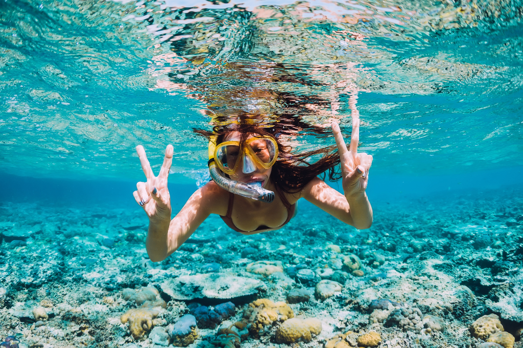 woman snorkeling and giving peace signs