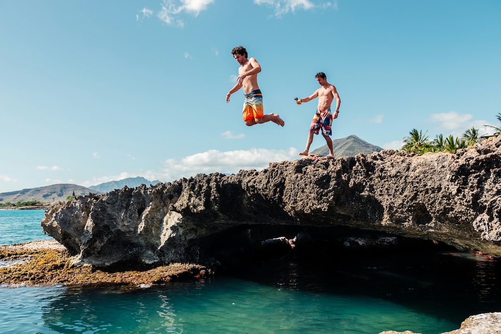 Two friends exploring cliffs and caves in o'ahu